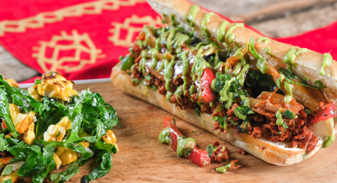 Chorizo Avocado Sanguche on a wooden board with vegetables on the side