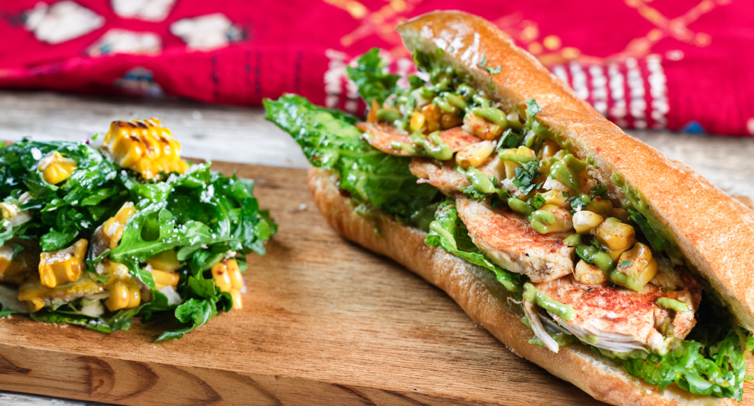 Chorizo Avocado Sanguche on a wooden board with vegetables on the side