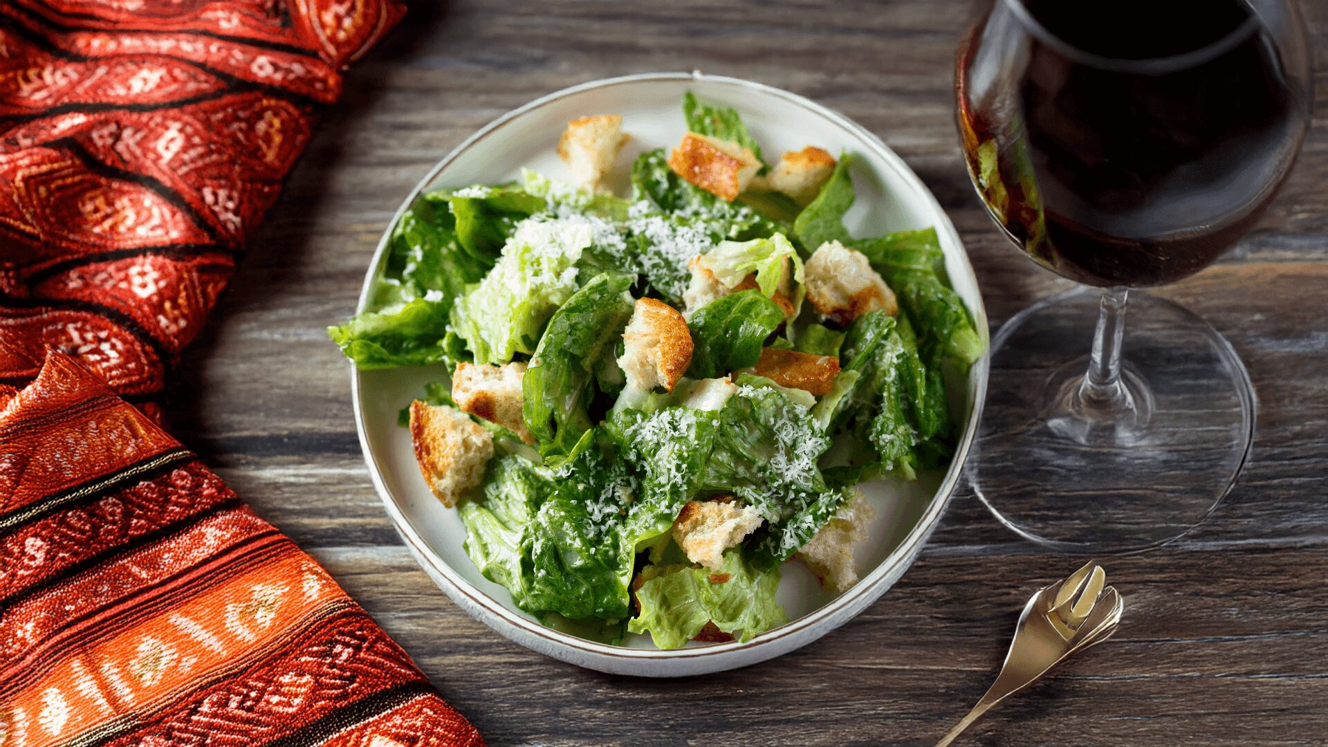 Latin Caesar Salad in a white bowl with wine glass