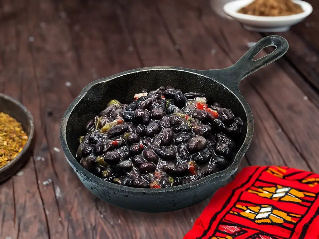 Savory black beans with spices in a skillet, paired with a colorful bowl of chili, inviting and flavorful.