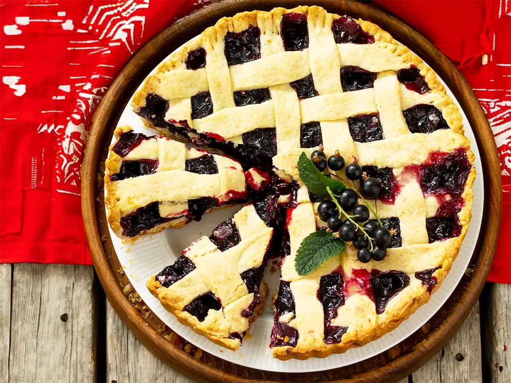 A delicious pie topped with fresh blueberries sits invitingly on a white plate, ready to be enjoyed.